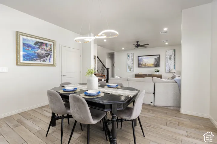 Dining area featuring wood-finish flooring, a modern sculptural light fixture, and recessed ceiling lighting