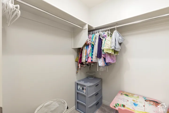 Walk-in closet featuring L-shaped built-in shelving and dual-tier metal hanging rods