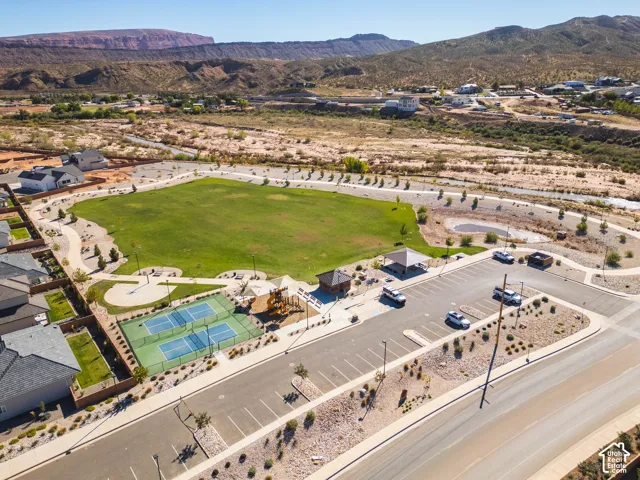 Expansive community green space featuring dual tennis courts, a paved walking path, covered pavilion, and desert-mountain backdrop
