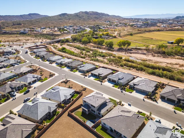 Aerial perspective of the residential community featuring tile roofing, paved streets, and mountain scenery