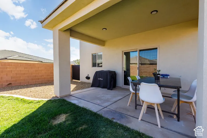 Covered concrete patio featuring recessed lighting, sliding glass door, and a partially fenced yard with gravel and turf landscaping