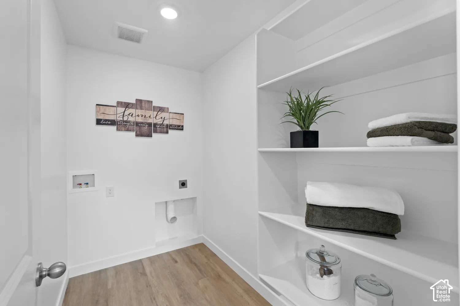 Built-in white shelving, wood-finish flooring, and recessed laundry hookups