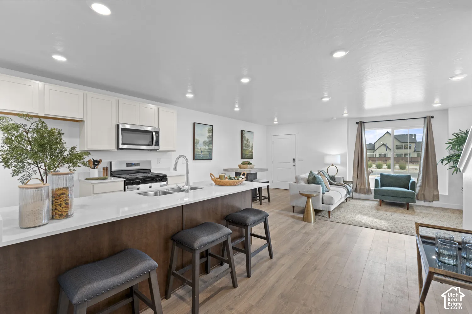 Open-concept kitchen featuring white cabinetry, a center island with light-colored countertops, wood-finish flooring, and recessed ceiling lighting