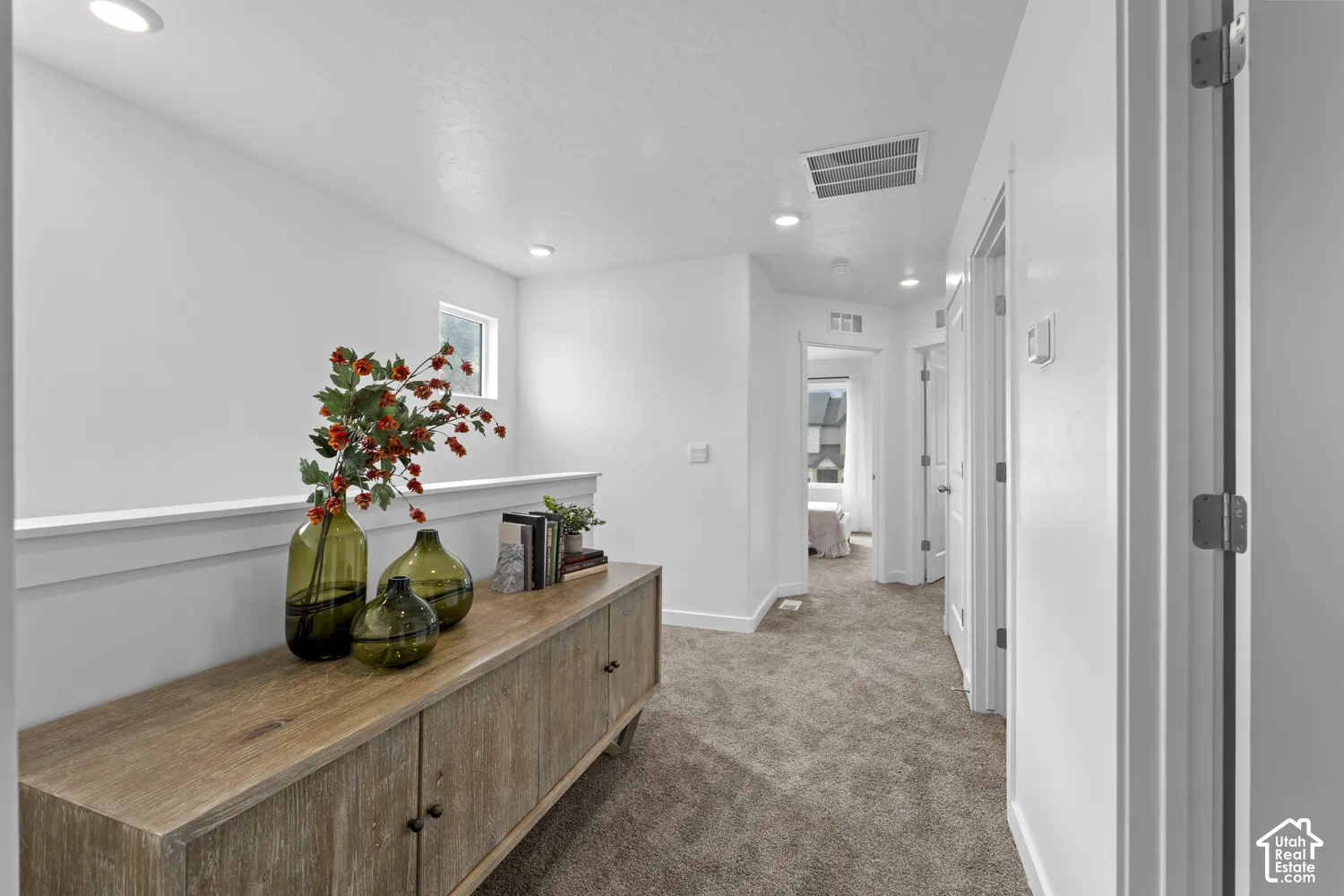 Hallway featuring neutral-toned carpeting, recessed ceiling lighting, and crisp white wall finishes
