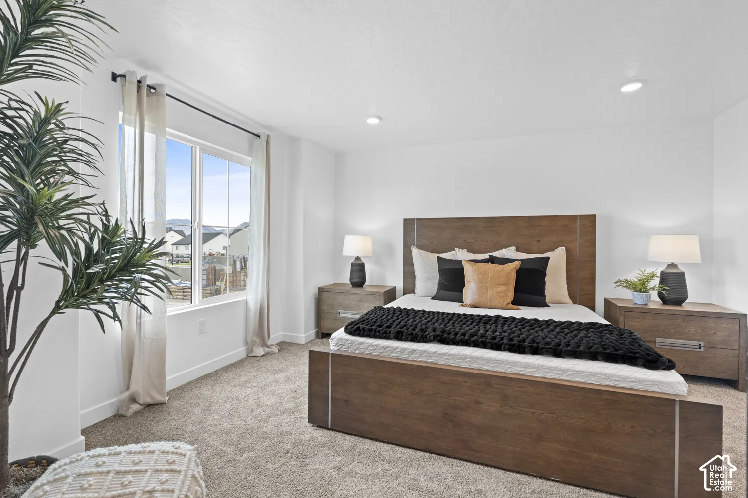 Neutral-toned carpeting, recessed ceiling lighting, and a window providing natural illumination