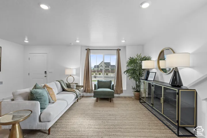 Living area featuring recessed ceiling lighting, a large window with natural light, wood-finish flooring, and a single-panel interior door