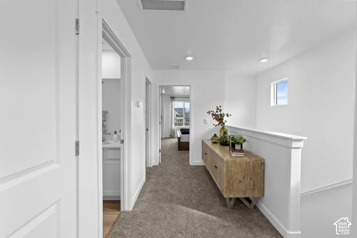Neutral-toned carpet flooring, recessed lighting, and a partial height wall featuring a flat cap railing