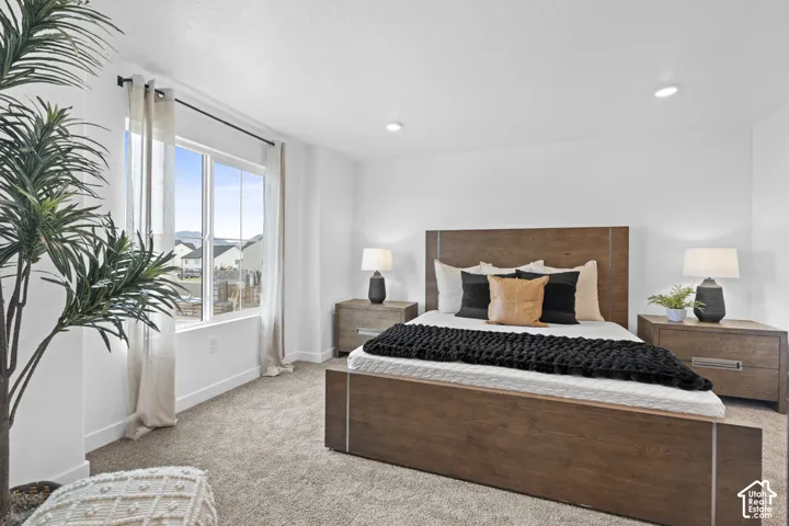 Neutral-toned carpeting, recessed ceiling lighting, and a window providing natural illumination