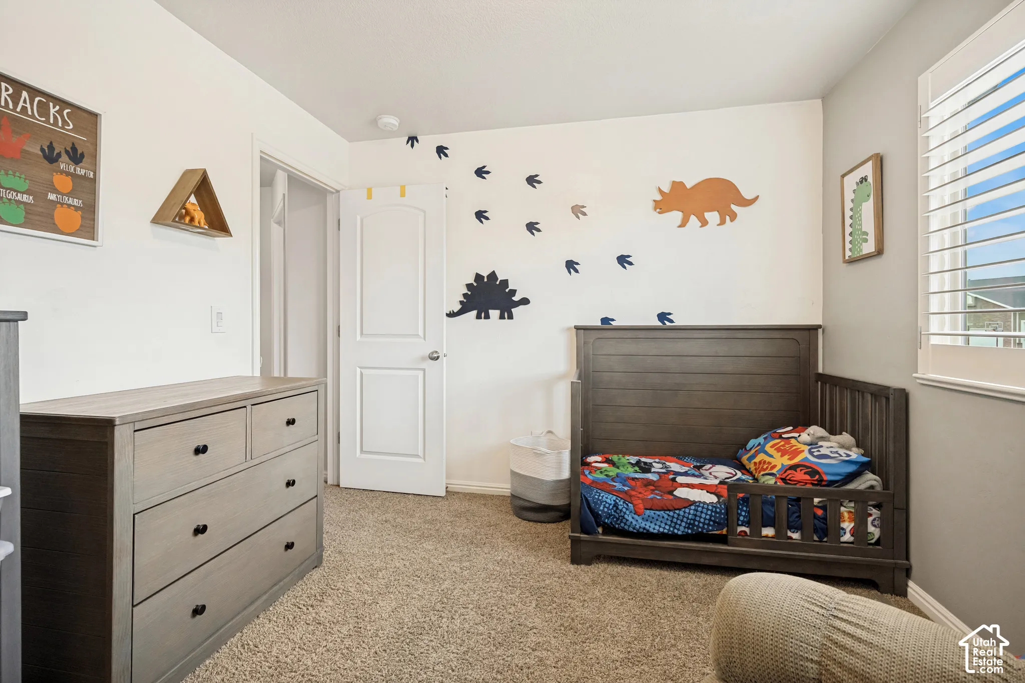 Room featuring neutral-toned carpeting, two-panel arched interior door, and window with plantation-style shutters