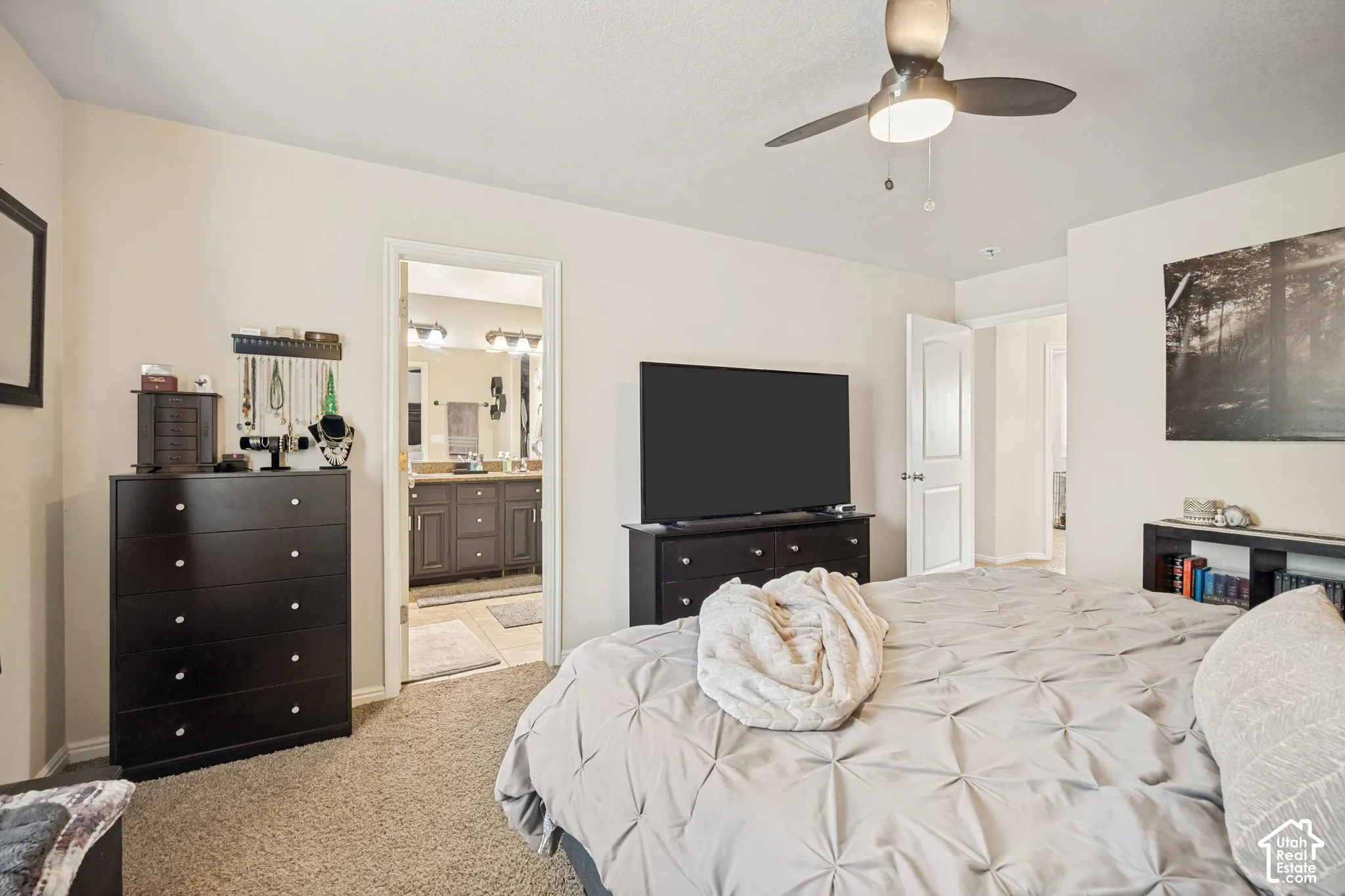 Neutral-toned interior space featuring wall-to-wall carpeting, a multi-blade ceiling fan with integrated lighting, and a six-panel interior door