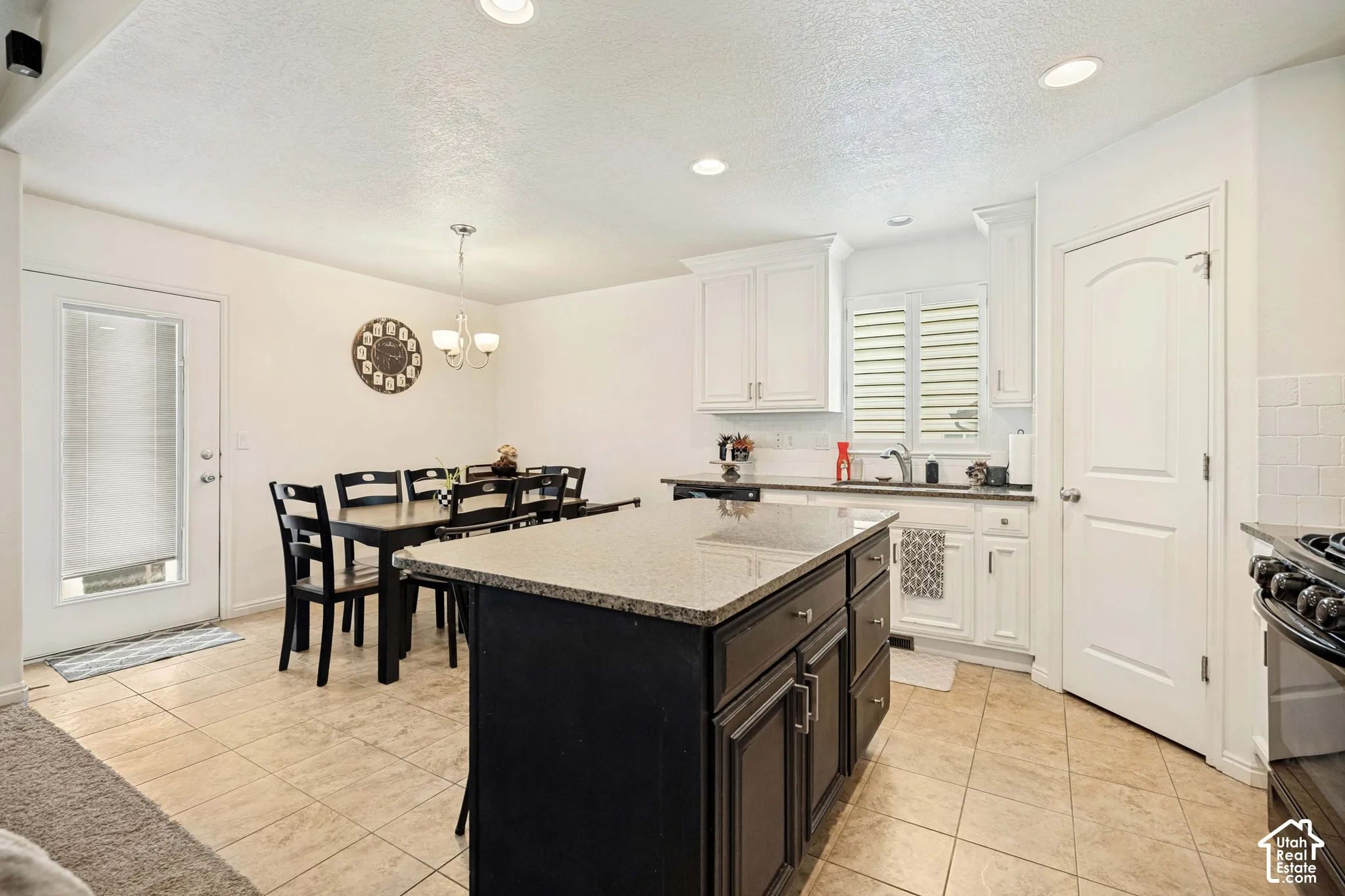 Kitchen featuring white upper cabinetry, center island with stone-finish countertop and dark-finish base cabinetry, recessed lighting, and tile flooring