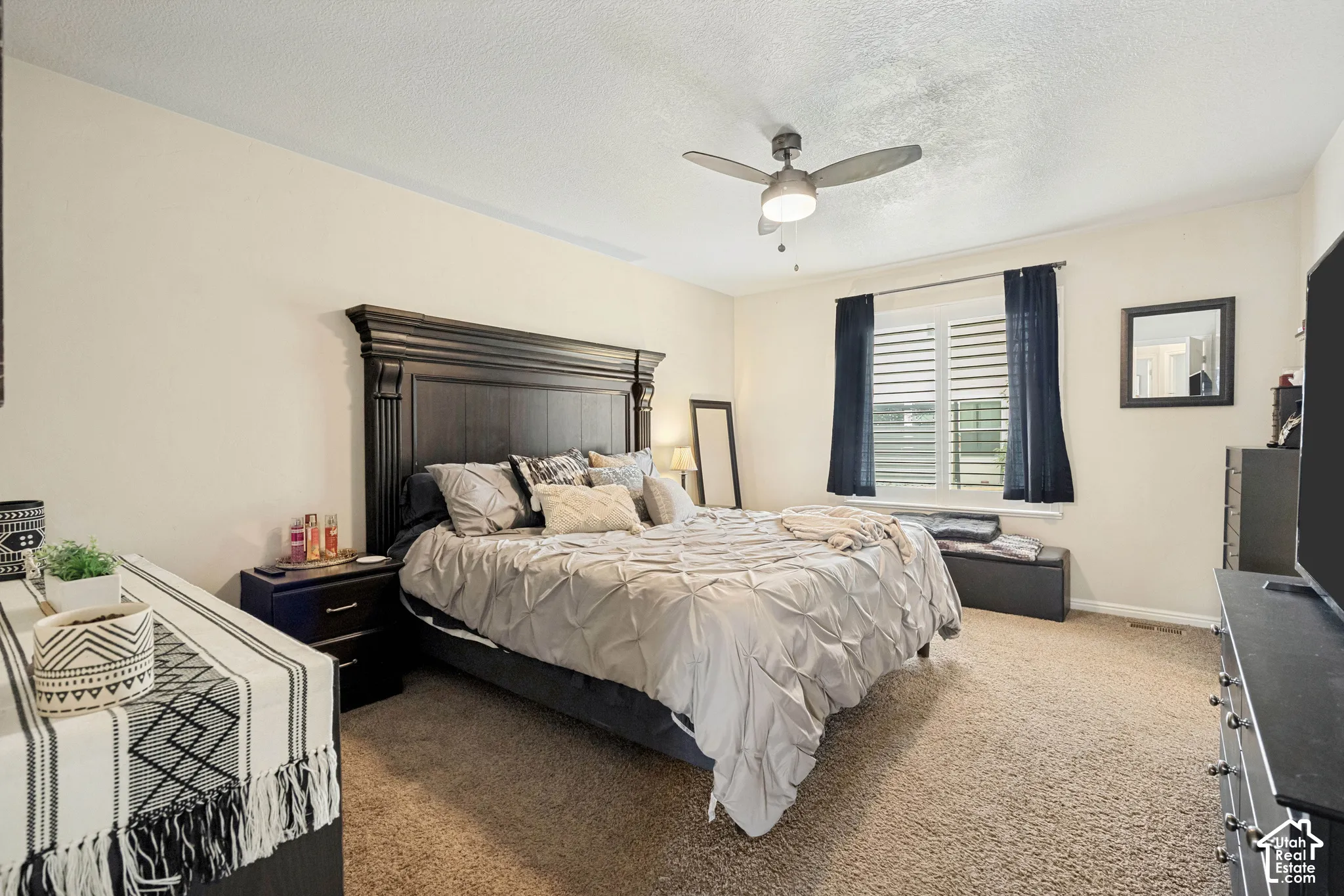 Neutral-toned interior featuring wall-to-wall carpeting, window shutters, and a ceiling fan with integrated lighting