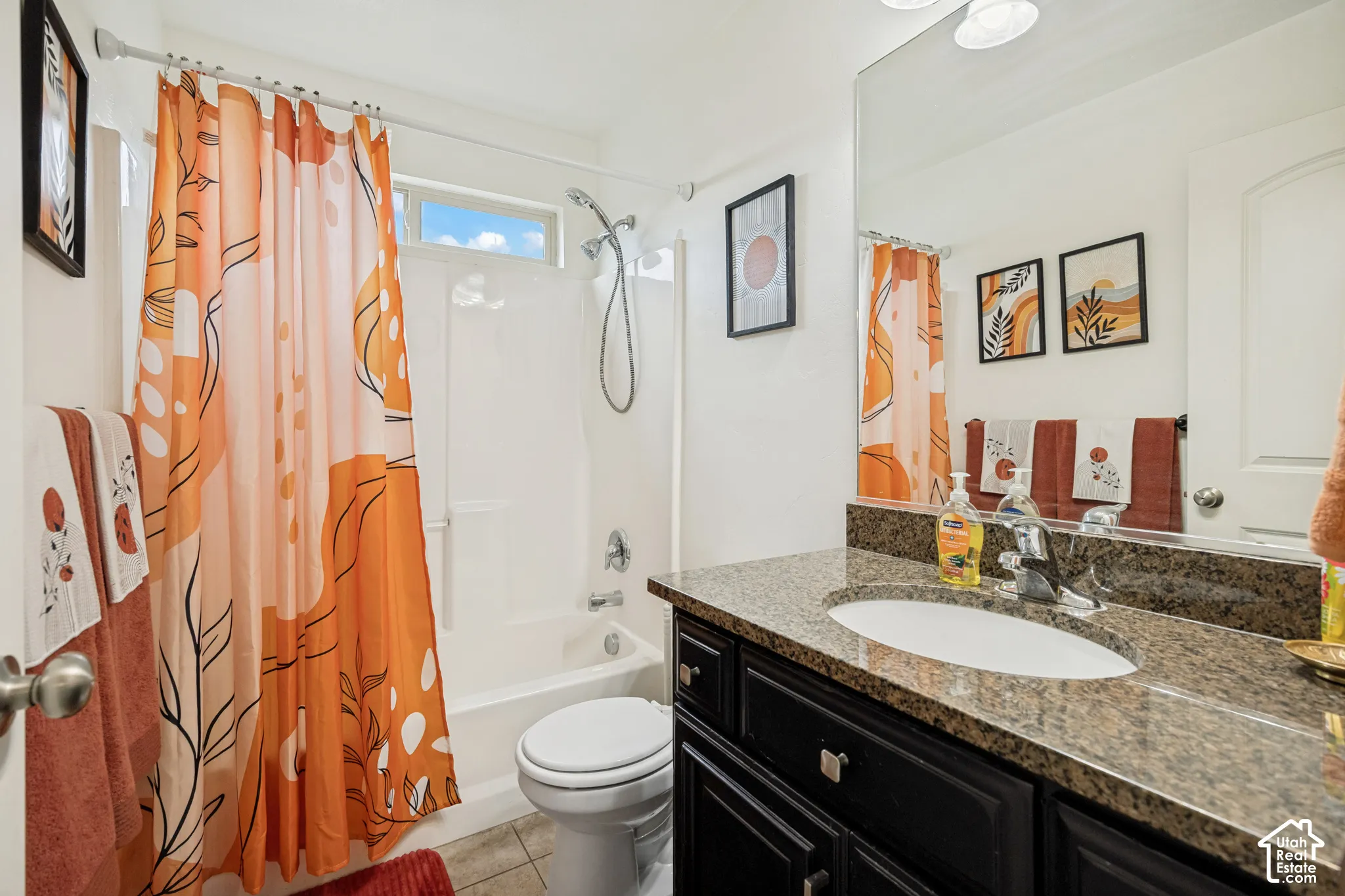 Bathroom featuring a dark wood-finish vanity with a stone countertop, an integrated oval sink, a wall-to-wall mirror, and a tub-shower combination with a handheld showerhead fixture