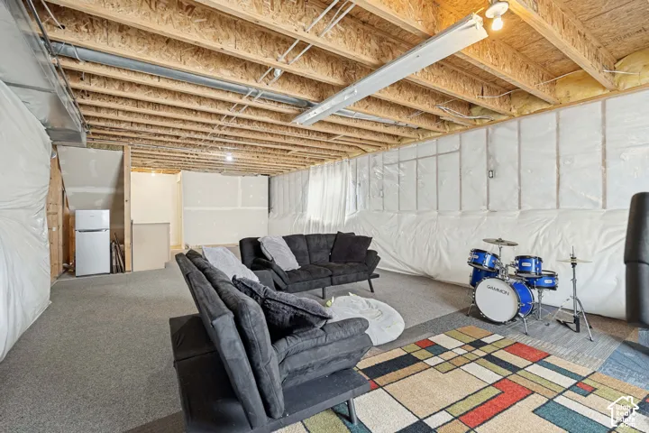 Unfinished lower level featuring exposed wood joist ceilings, wall vapor barriers, and wall-to-wall carpeting