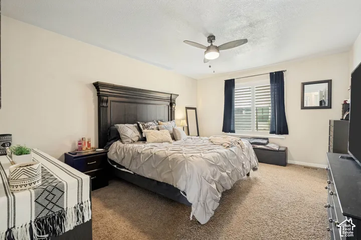 Neutral-toned interior featuring wall-to-wall carpeting, window shutters, and a ceiling fan with integrated lighting