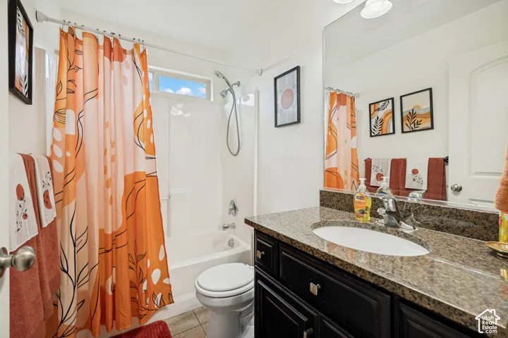 Bathroom featuring a dark wood-finish vanity with a stone countertop, an integrated oval sink, a wall-to-wall mirror, and a tub-shower combination with a handheld showerhead fixture