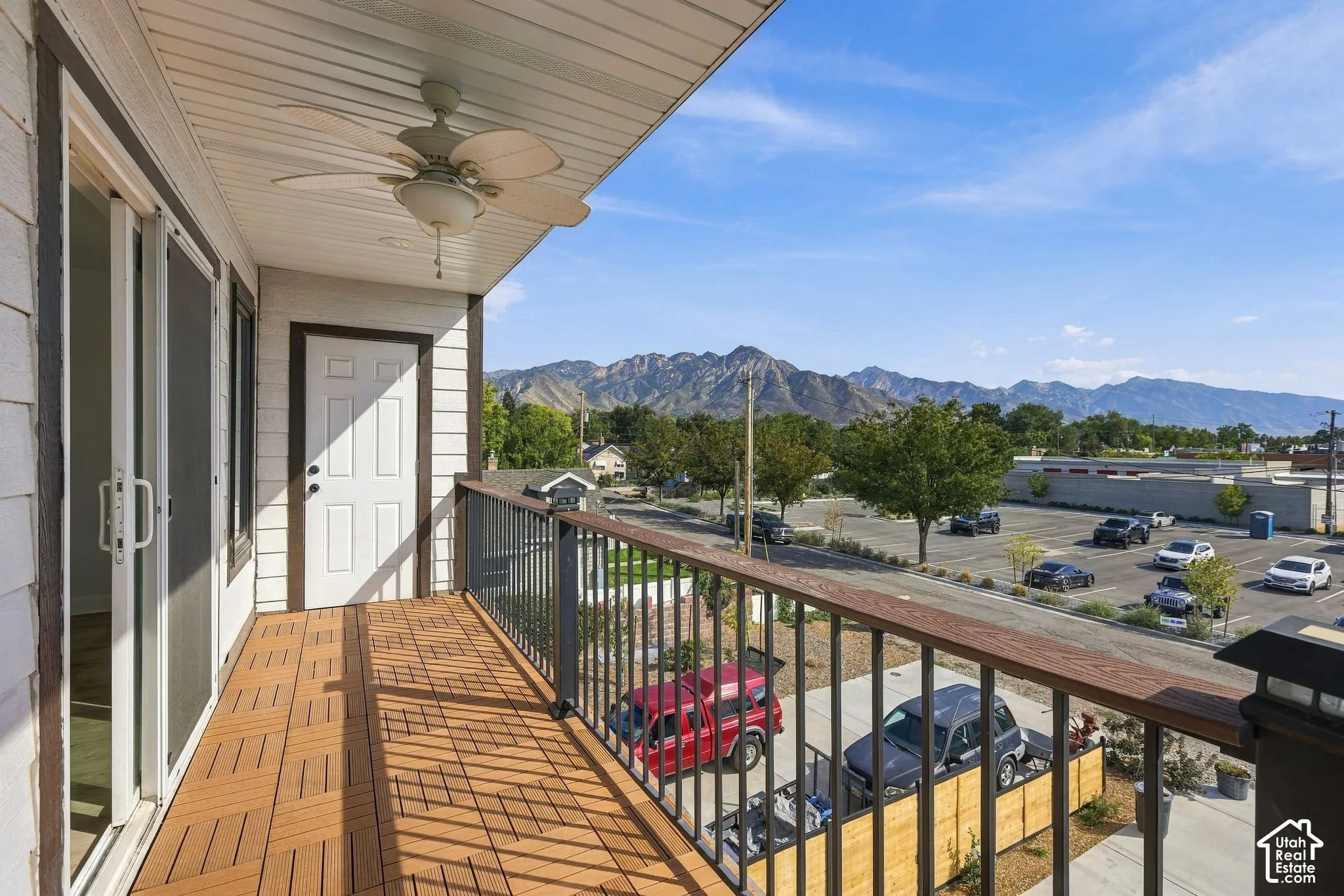 Balcony featuring wood-finish flooring, a ceiling fan, sliding glass doors, and a metal railing