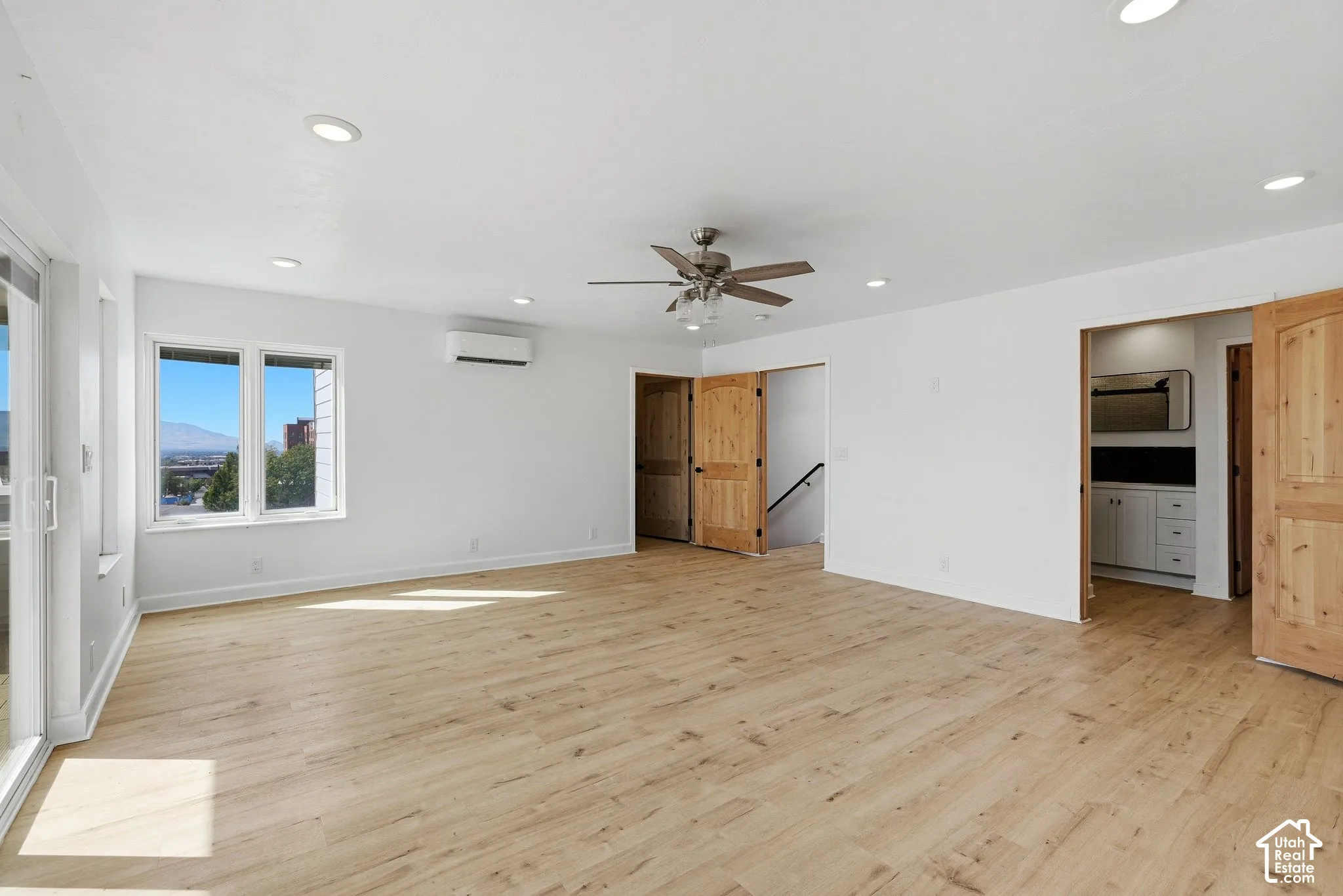 Recessed lighting and a ceiling fan illuminate this expansive room, featuring wood-finish flooring