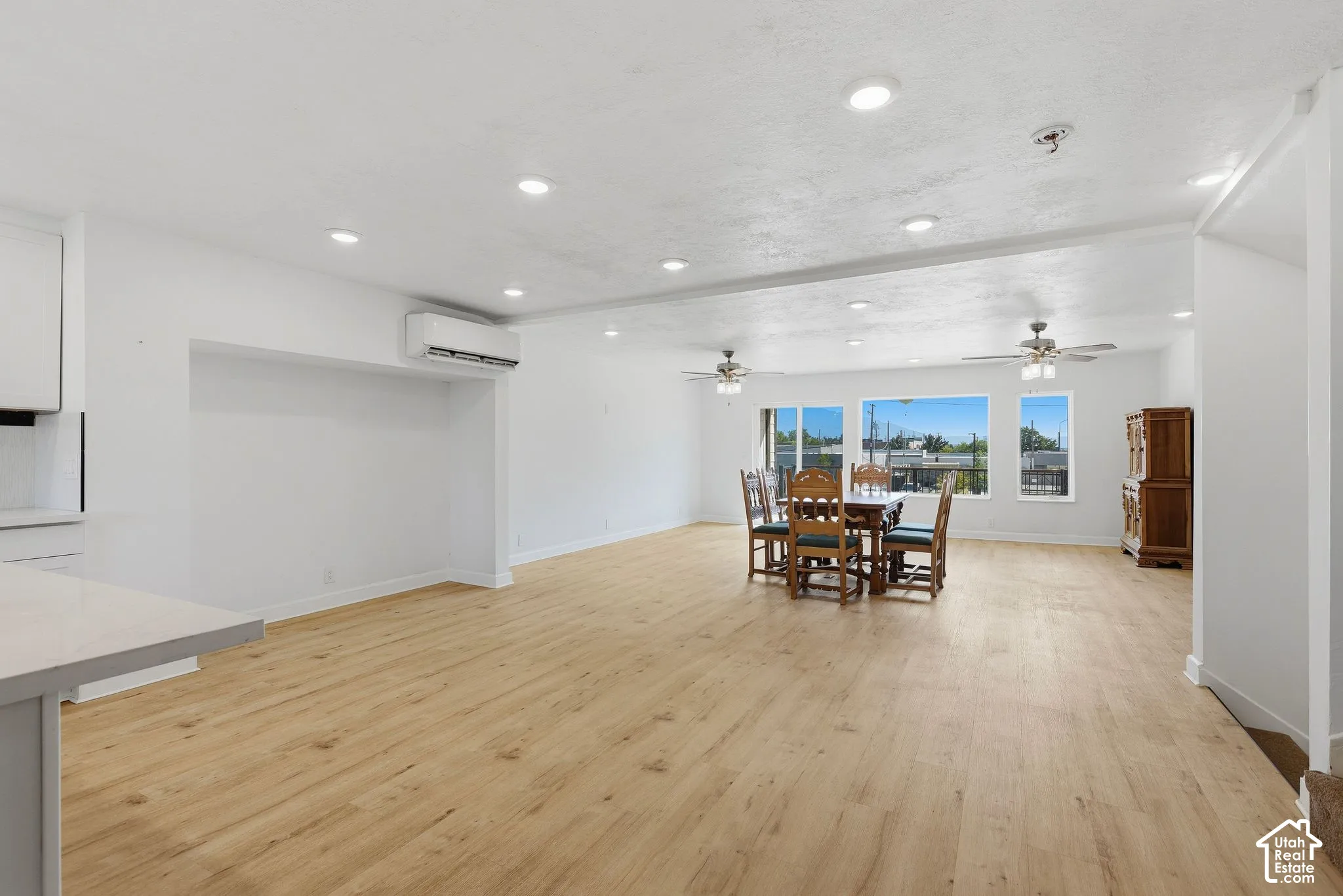 Spacious open-concept room with wood-finish flooring, recessed lighting, and large windows