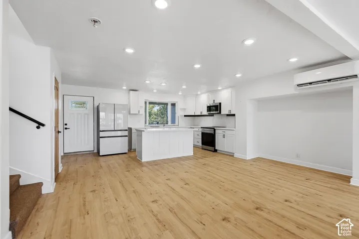 Wood-finish flooring, recessed lighting, white cabinetry, kitchen island with shiplap-style paneling, and a mini-split system