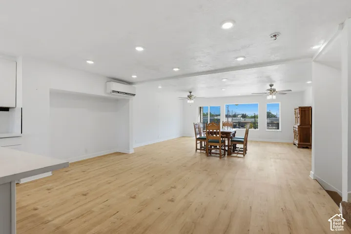 Spacious open-concept room with wood-finish flooring, recessed lighting, and large windows