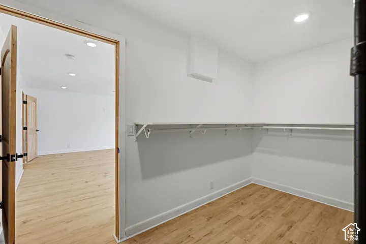 Walk-in closet with white walls, wood-finish flooring, and recessed lighting