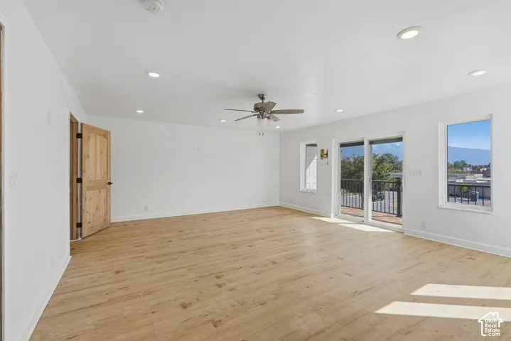 Spacious room featuring wood-finish flooring, recessed lighting, a ceiling fan, and sliding glass door access to an exterior balcony with black railings