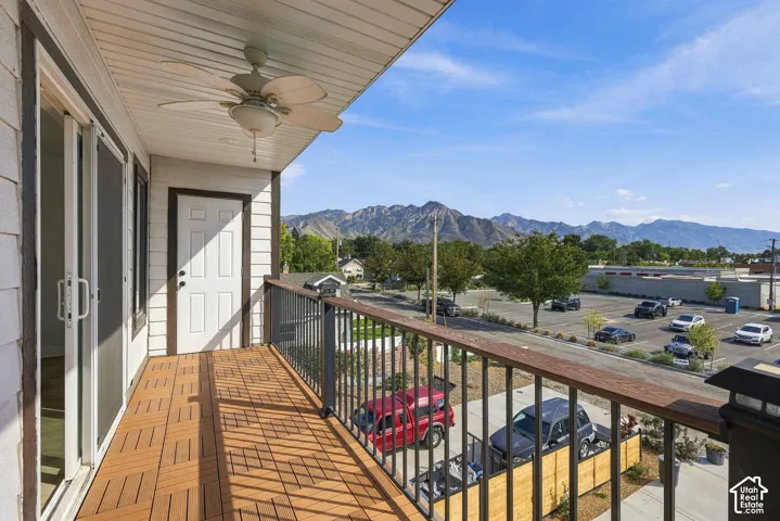 Second-story balcony with composite decking, black metal railing, ceiling fan, and sliding glass doors