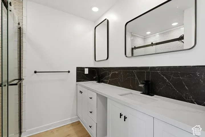 Dual vanity with integrated rectangular sinks, white cabinetry, matte black hardware and fixtures, and a black marble-patterned backsplash