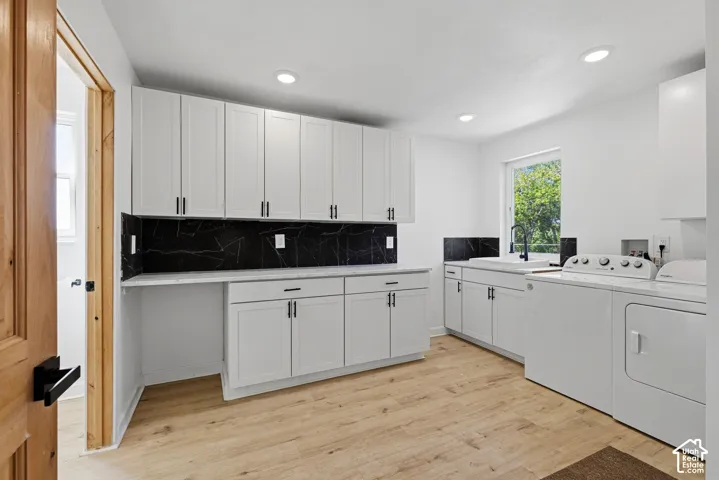 White cabinetry, solid surface countertops, black backsplash, wood-finish flooring, and recessed lighting