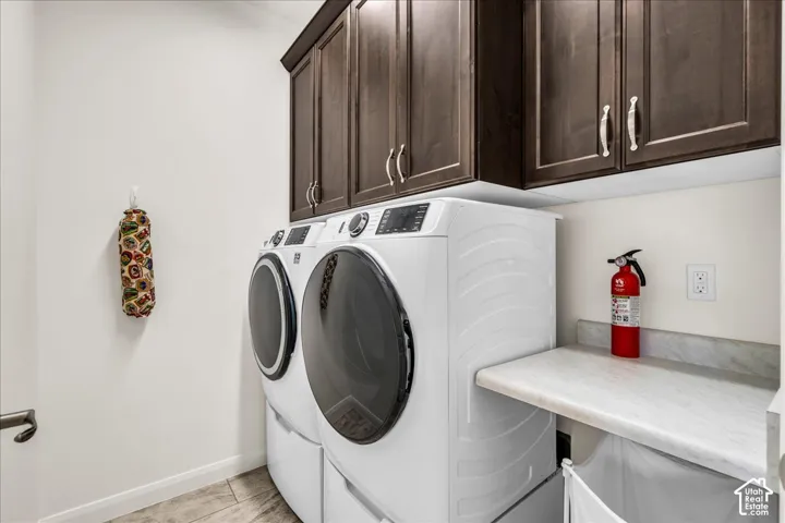 Laundry room featuring dark wood-finish cabinetry, stone-finish countertops, and tile flooring
