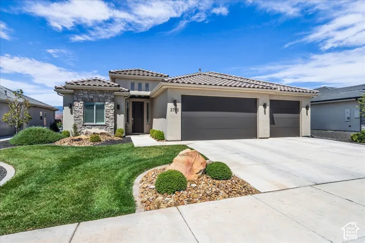 Stucco exterior featuring stone veneer accents, a tiled roof, and a three-car garage