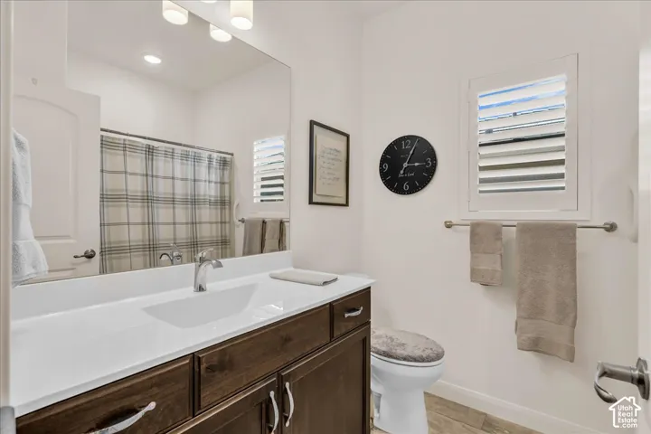 Bathroom featuring a dark wood-finish vanity, integrated rectangular sink, large wall-mounted mirror, polished chrome faucet, and plantation shutter window treatment