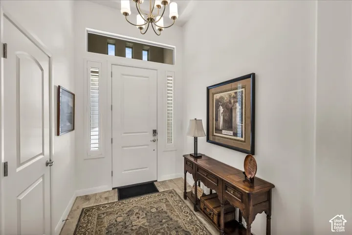 Entryway featuring high ceilings, a solid core door with sidelights, transom window, and a multi-arm chandelier