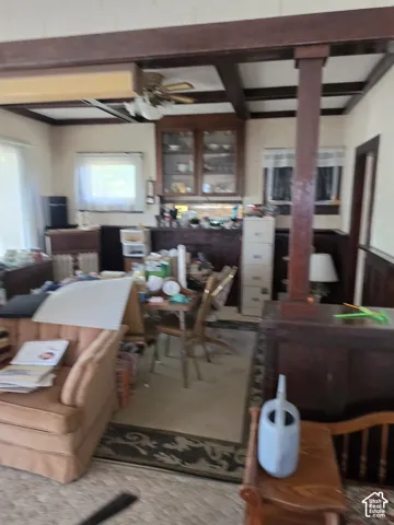 Interior space featuring dark wood-finished ceiling beams, built-in glass-front cabinetry, a dark wood post support, and dark wood-finished wainscoting