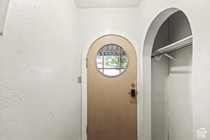 Arched doorway featuring a circular window entry door and a built-in arched alcove with a clothes rod and shelving
