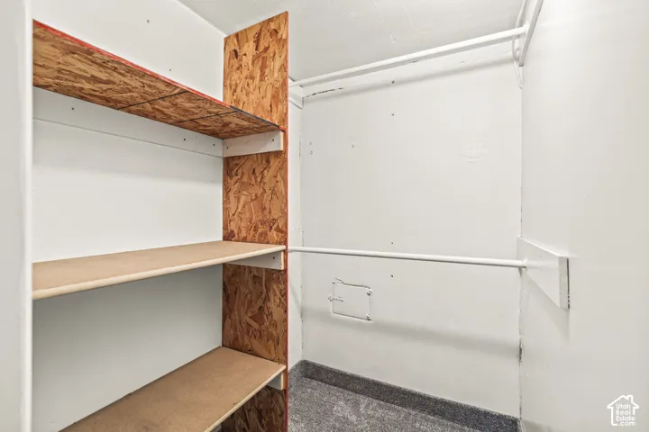 Storage area featuring oriented strand board shelving and dual white metal hanging rods