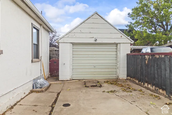 Detached single-car garage featuring a roll-up door, horizontal siding, and concrete driveway