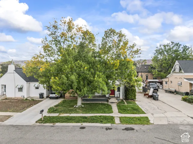 Exterior featuring a white facade, covered front porch, concrete driveway, and mature landscaping