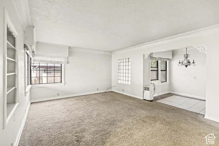 Living area featuring built-in shelving, glass block accent wall, carpeted flooring, decorative corbels, and a multi-arm chandelier