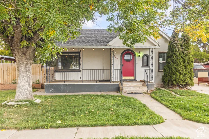 Single-story exterior featuring a covered front porch with iron railings, arched entryway, and a concrete walkway