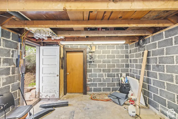 Exposed ceiling joists, concrete masonry unit walls, concrete flooring, and solid core door