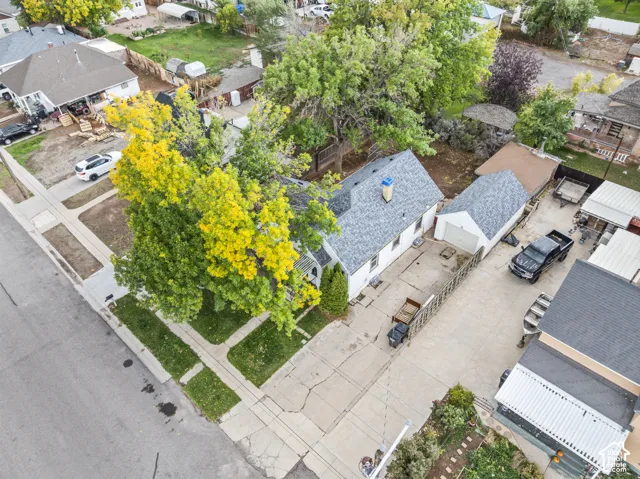 Gable-roof residence featuring an asphalt shingle roof, detached single-car garage, concrete driveway, and mature landscaping
