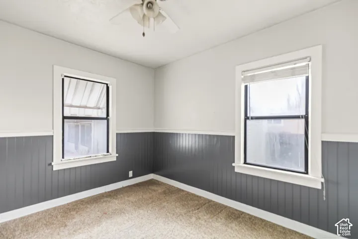 Room featuring dual windows, gray beadboard wainscoting, carpeted flooring, and a ceiling-mounted light fixture