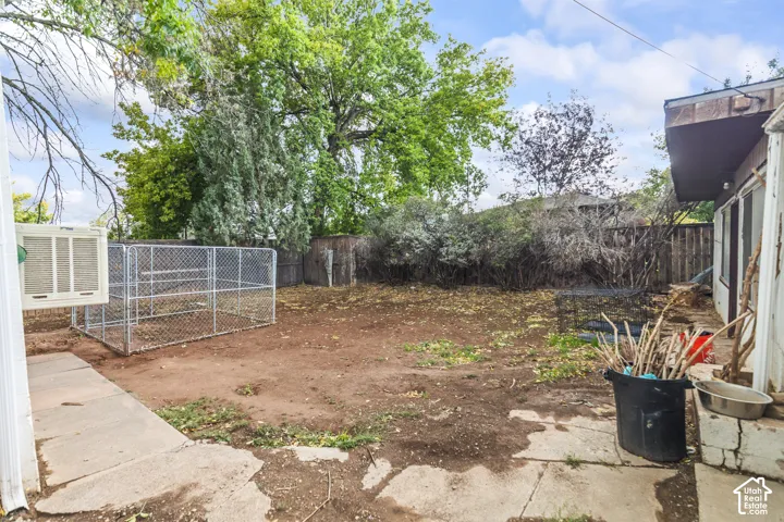 Private backyard featuring a chain-link enclosure, perimeter wood fencing, and mature trees