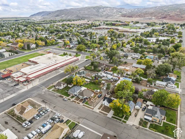 Aerial perspective featuring established neighborhood infrastructure, mature trees, and prominent mountain range backdrop