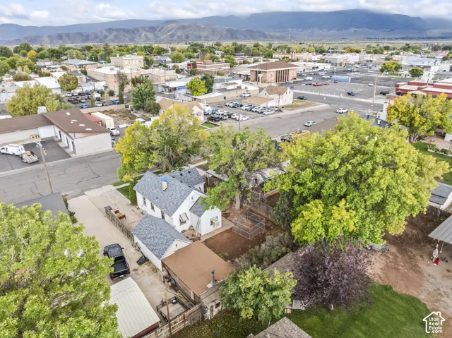 Aerial perspective showcasing a property with mature trees, a multi-section roofline, and mountain scenery