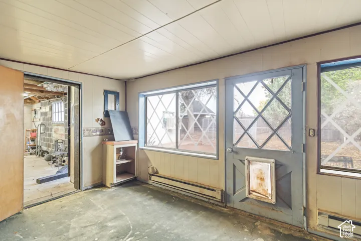 Enclosed room featuring paneled walls, sliding glass window, diamond-patterned glass pane door, and built-in storage cabinetry