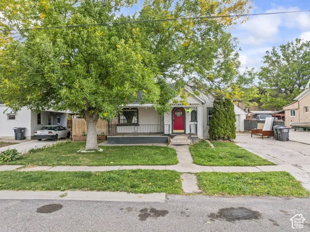 Exterior facade featuring a covered front porch, wrought iron railing, and concrete driveway
