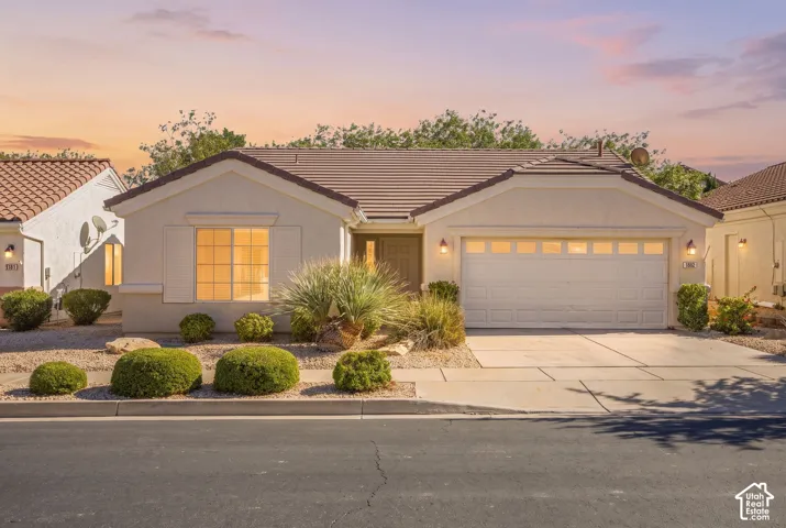 Stucco exterior featuring a tiled roof, multi-panel garage door, and low-maintenance desert landscaping